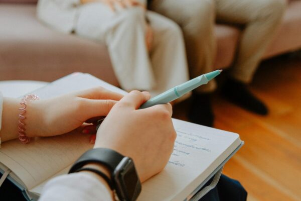 A therapist takes notes while counseling a couple in an indoor session.