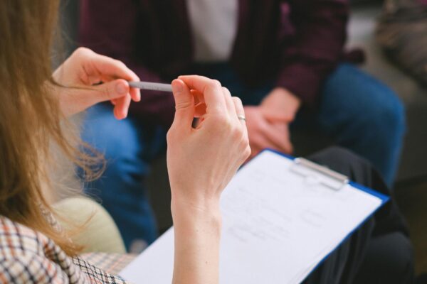 A therapist with a clipboard conducting a counseling session with clients.